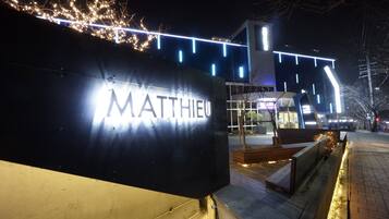 A building with a sign reading "MATTHEU" and modern architecture with illuminated lines.