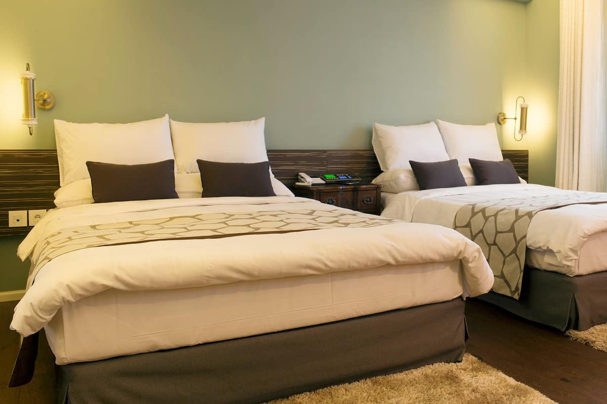 Une chambre avec un grand lit pour deux personnes, deux lits simples, une table de chevet et une lampe.