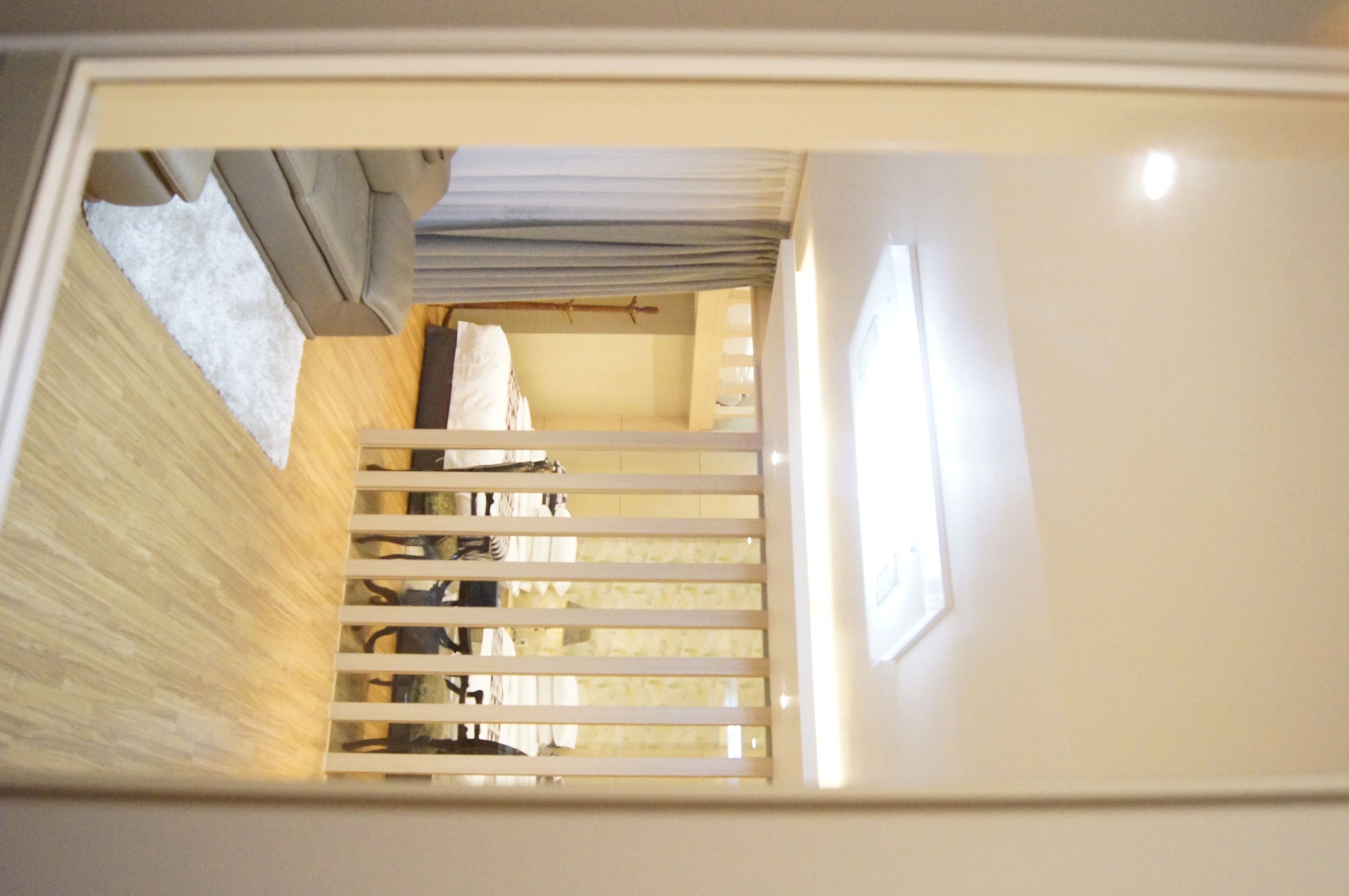 Un escalier étroit avec des rampes en bois mène à une pièce où se trouvent un lit et une fenêtre.