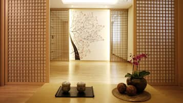 Een traditionele Japanse kamer met tatami vloerbedekking, een shoji scherm, een kalligrafiewand en een kleine tafel met een vaas en twee keramische bekers.
