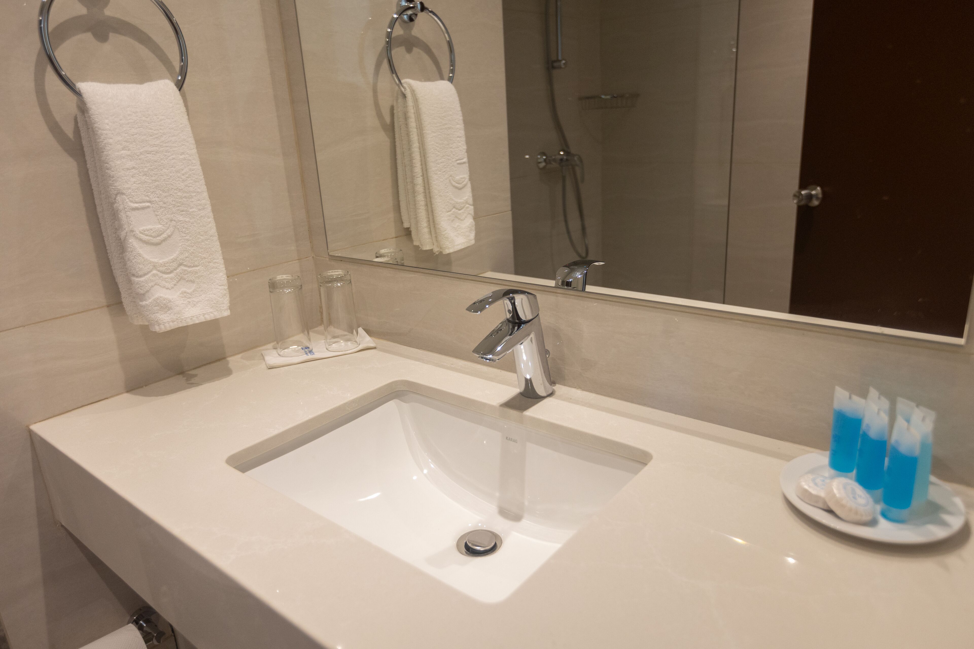 A bathroom with a white sink, a mirror, and a towel rack.