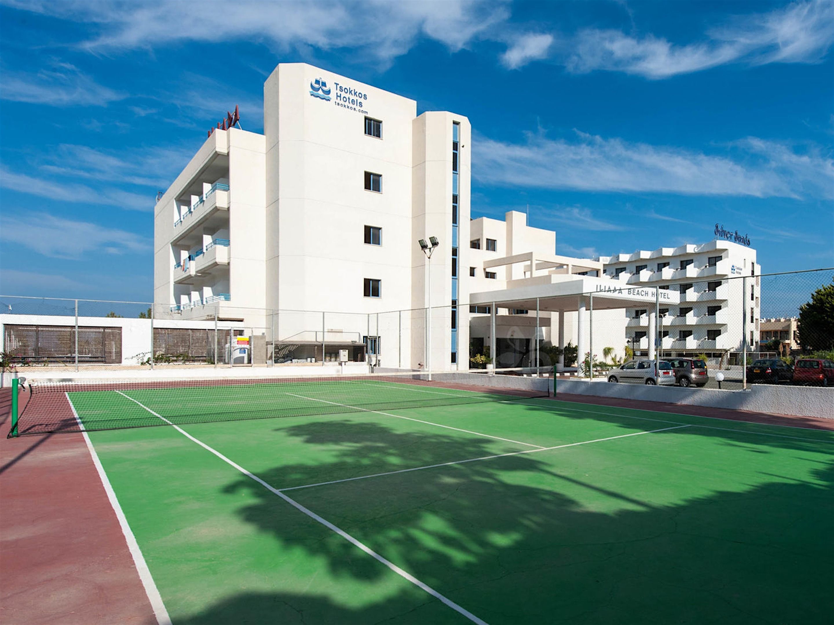 Een modern hotel met een tennisbaan ervoor.