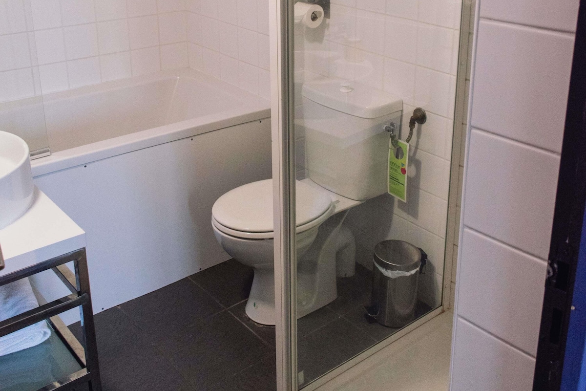 Un baño con inodoro, cabina de ducha y cubo de basura.