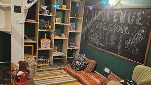 Un salón de juegos infantil acogedor, con una pared de pizarra, estanterías de madera y una alfombra a rayas.