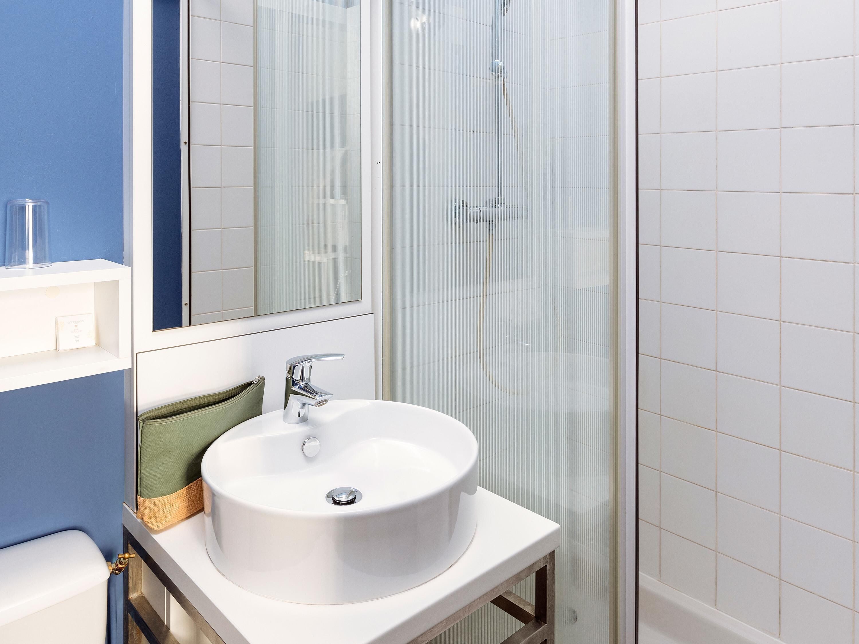 A bathroom with a white sink, a mirror, and a shower enclosure.