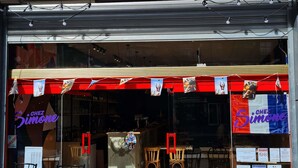 Un restaurante con terraza, un toldo rojo y un letrero que dice "Chez Simone".