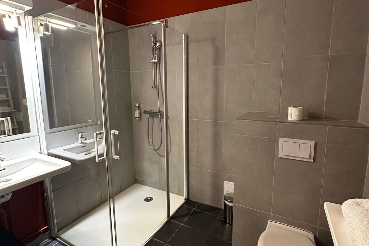 Un baño moderno con ducha de mampara de vidrio, un lavabo blanco y un inodoro.