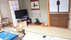 Una habitación japonesa tradicional con suelo de tatami, televisor, pantalla shoji y puerta corredera.