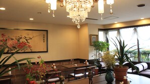 Un restaurante con candelabro, asientos y plantas en macetas.