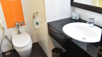 Um banheiro moderno com vaso sanitário branco, pia e chuveiro.