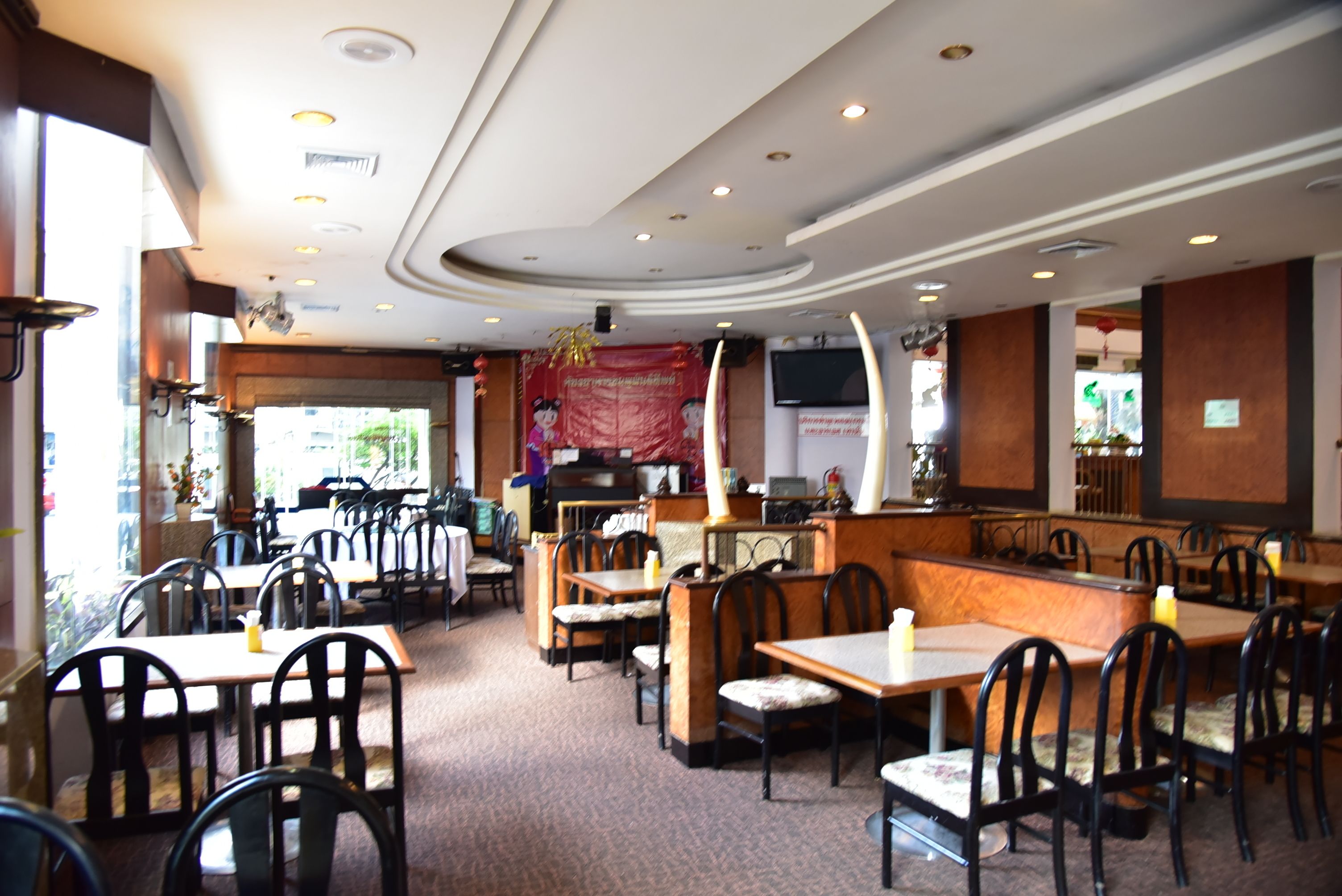 Un restaurante con cabinas y mesas, una barra y una pantalla de televisión.