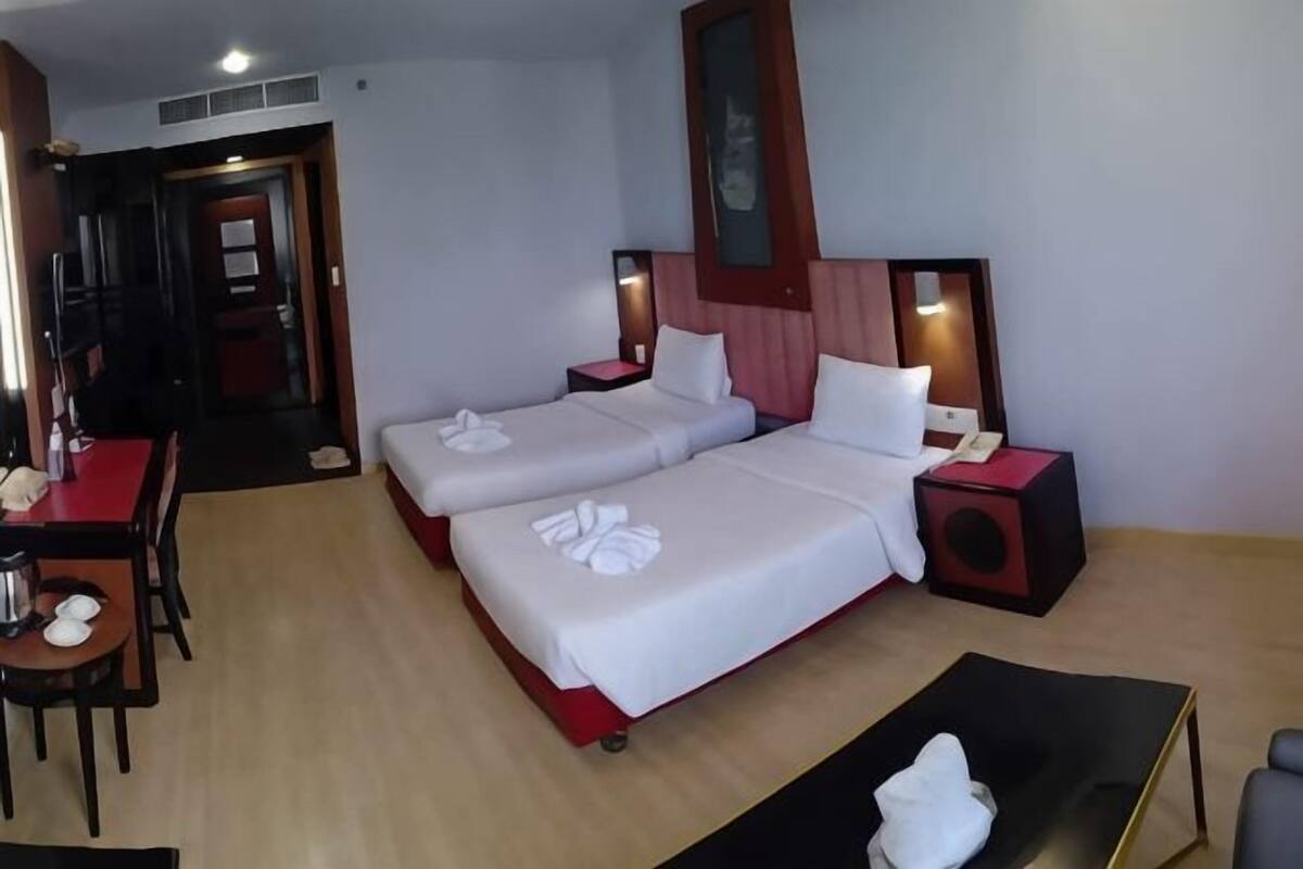 A hotel room with two beds, a desk, a chair, and a small table.