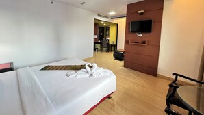 Een hotelkamer met een bed, een televisie bevestigd aan een houten paneel, een bureau en een stoel.