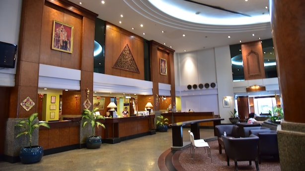Een hotel lobby met een receptiebalie, een zithoek en decoratieve elementen.