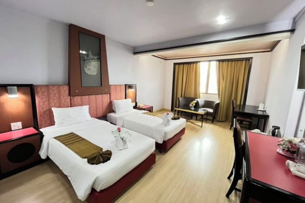 A hotel room with two beds, a desk, a chair, and a window with curtains.