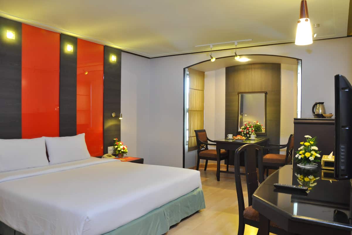 A hotel room with a bed, a desk, and a TV.