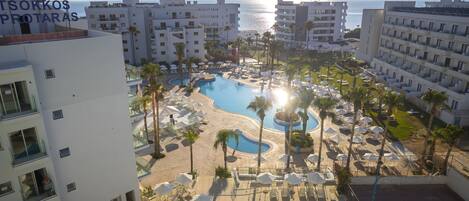 Un resort con piscina, tumbonas y vista al mar.