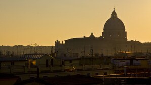 A large building with a prominent dome, surrounded by smaller structures and a hilly landscape. - Domus Giulio Cesare (Rome)