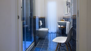 A modern bathroom with a glass shower enclosure, a freestanding bathtub, a sink, and a chair. - Domus Giulio Cesare (Rome)