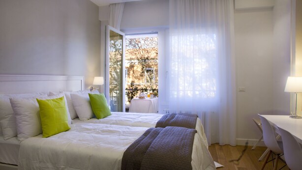 A bedroom with two beds, a desk, and a view of the outdoors. - Domus Giulio Cesare (Rome)