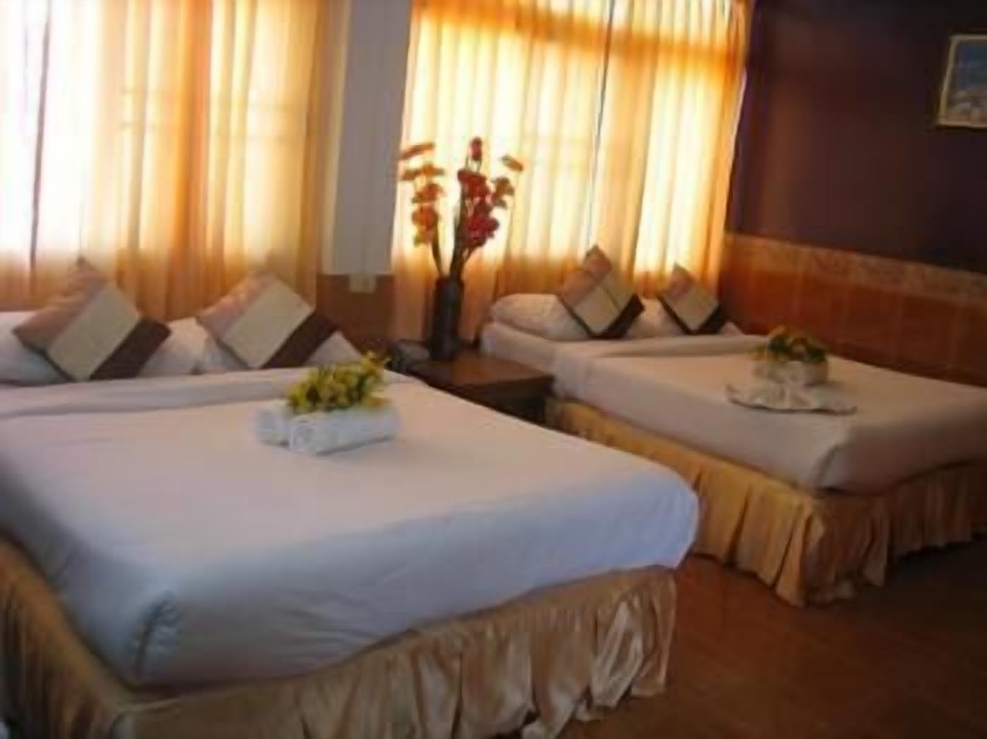 Habitación de hotel con dos camas, una mesita de noche y un florero con flores.