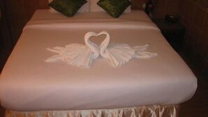Ein Bett mit einem Bettbezug, der ein Herzförmiges Handtuchdesign zeigt.