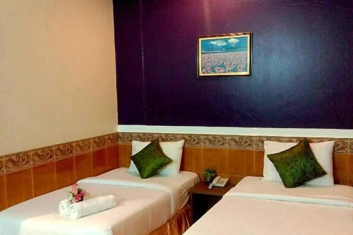 Une chambre d’hôtel avec deux lits, une table de chevet, un téléphone et un tableau encadré au mur.
