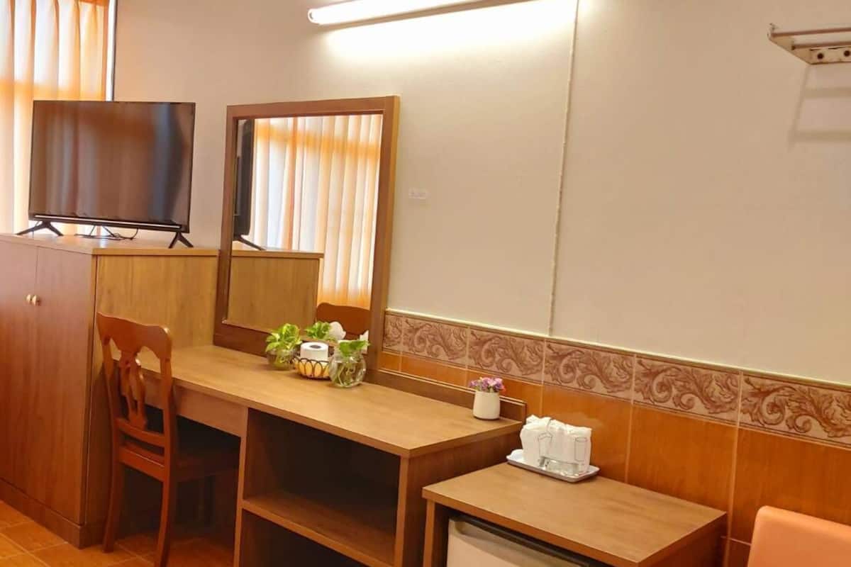 Une chambre d’hôtel équipée d’un bureau, d’une chaise, d’une télévision et d’un petit réfrigérateur.