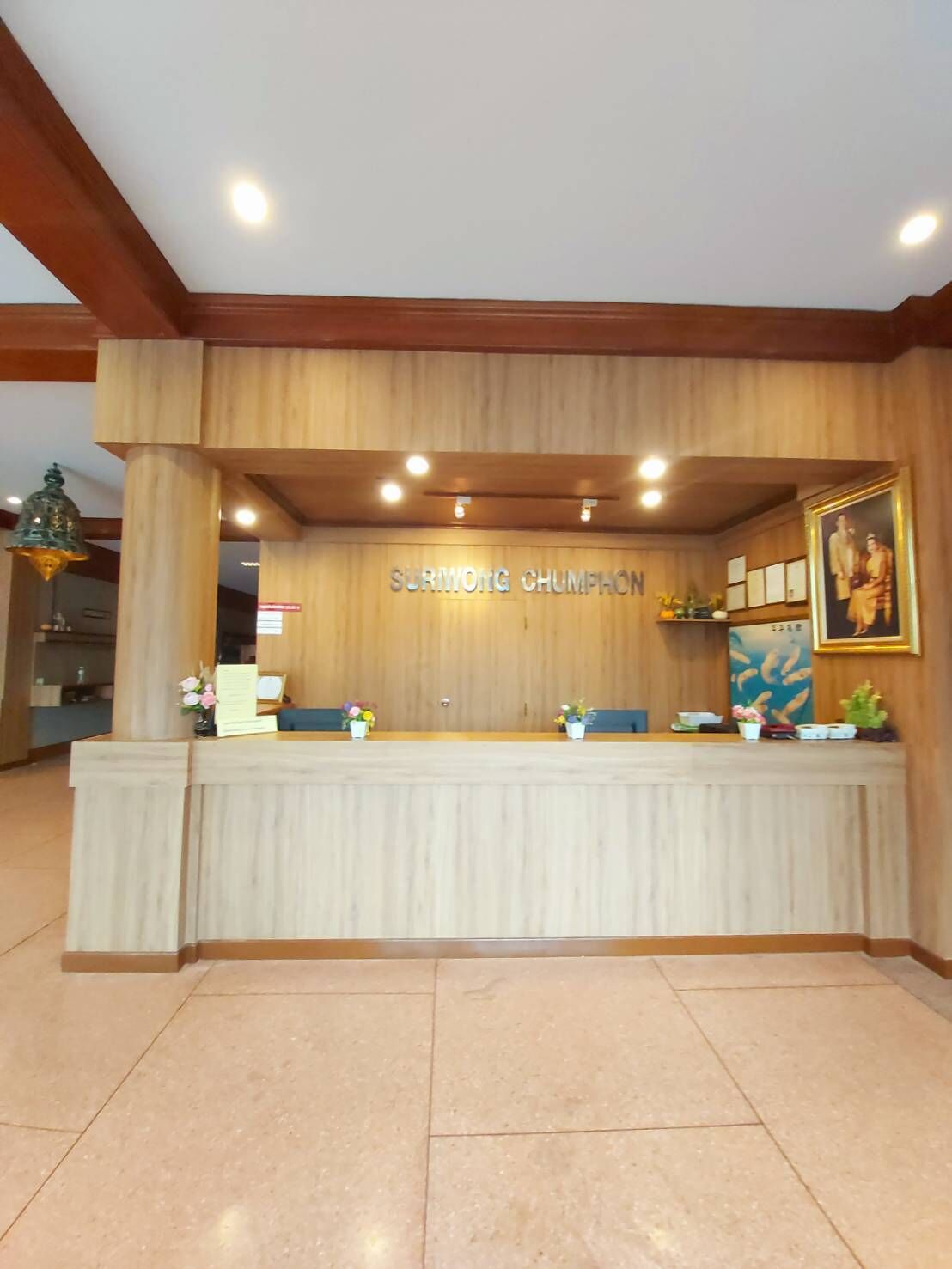 A reception desk with a wooden finish and a sign reading "SURMONG CHUMPHON".