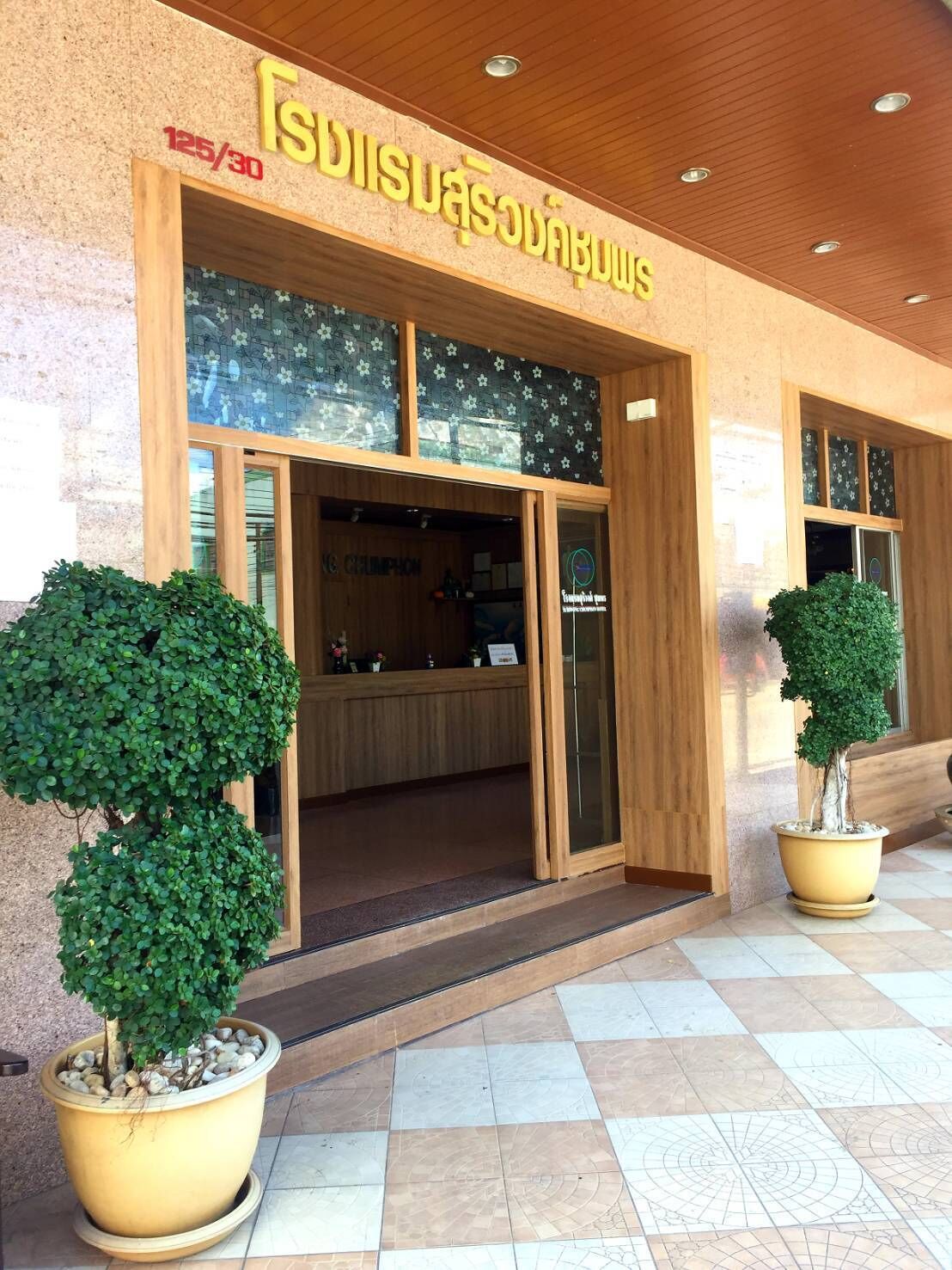 A building entrance with a sign reading "TISUDISUABANBUYS" and a reception desk inside. There are two potted trees in front.