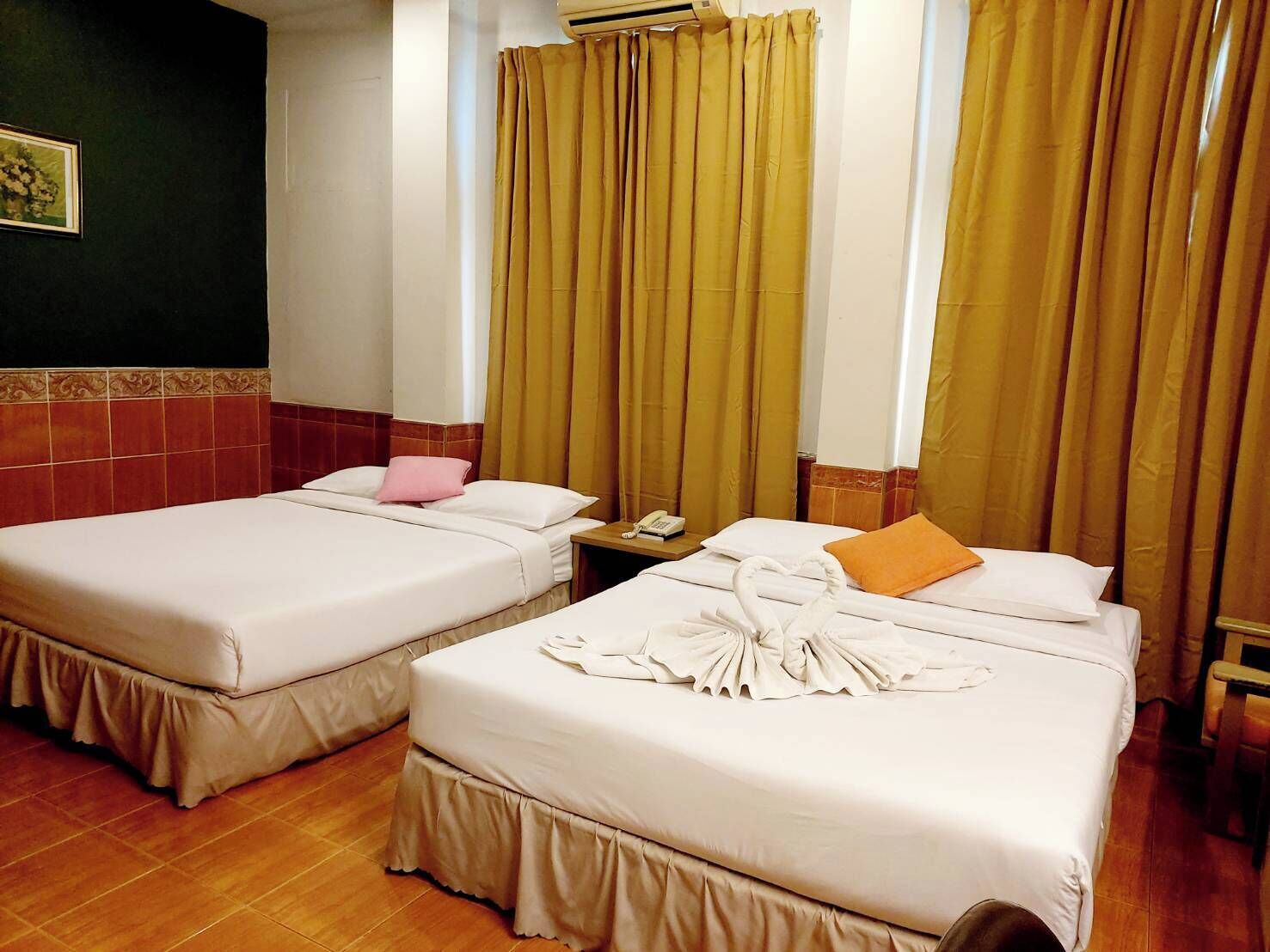A hotel room with two beds, a nightstand, a telephone, and a window with curtains.