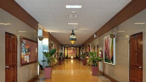 Un pasillo de hotel con piso pulido, puertas de madera y plantas en macetas.