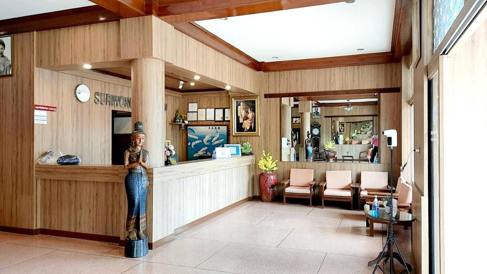 Zona de recepción con mostrador de madera, una estatua, televisor y área de asientos.