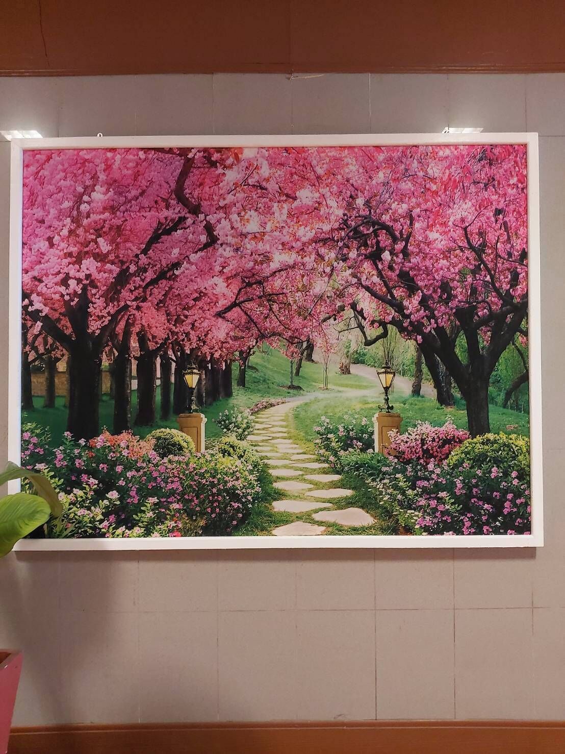 A framed painting of a cherry blossom path in a garden.