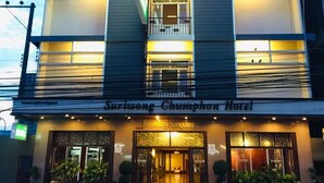 Un hotel de varios pisos con fachada moderna, balcones en cada nivel y una entrada bien iluminada.