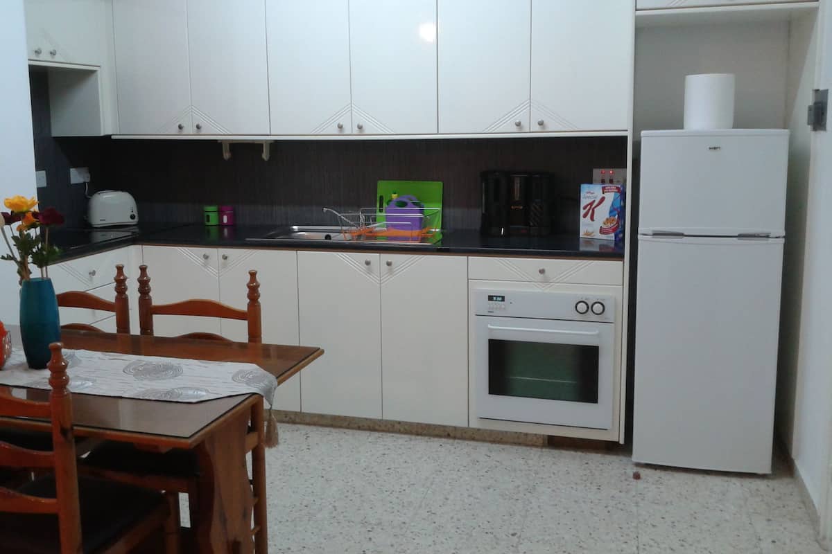A kitchen with white cabinets, a refrigerator, a coffee maker, and a toaster.