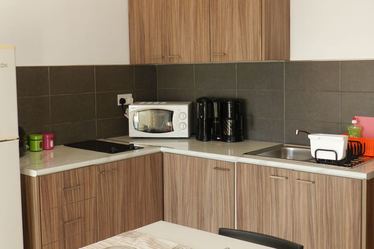 A compact kitchen with wooden cabinets, a microwave, a coffee maker, and a toaster.
