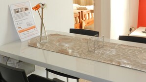 A hotel room with a white table, black chairs, a vase with flowers, and a notice board with information. - Elenapa Holiday Apartments (Ayia Napa)