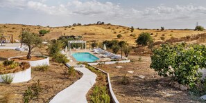 Un área exterior ajardinada con piscina, mobiliario y un pérgola.