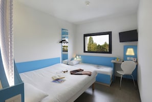 A hotel room with a bed, a desk, a chair, a TV, and a window with a view.