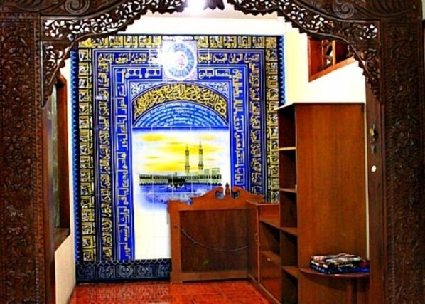 Una habitación con pared de diseño azul y dorado, una puerta de madera y un pequeño escritorio de madera con una silla.