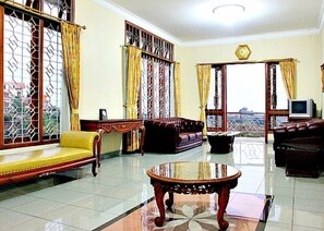 A spacious living room with a yellow sofa, a dark brown sofa, and a wooden coffee table. - De Goti Dago Pakar (Bandung)