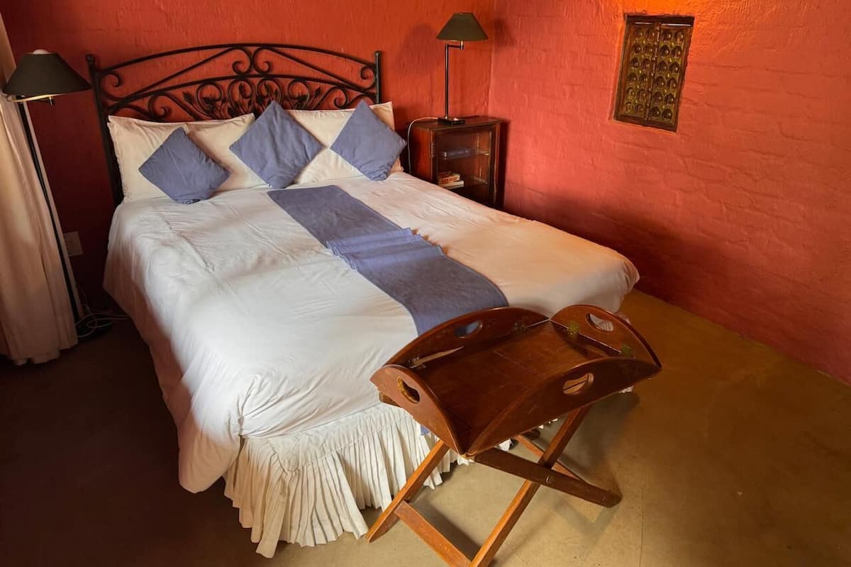 A bed with a wooden headboard, a bedside table, and a nightstand with a lamp.