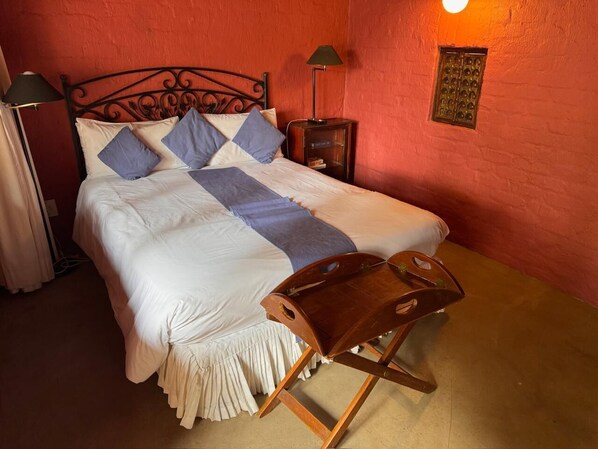 A bed with a wooden headboard, a bedside table, and a nightstand with a lamp.