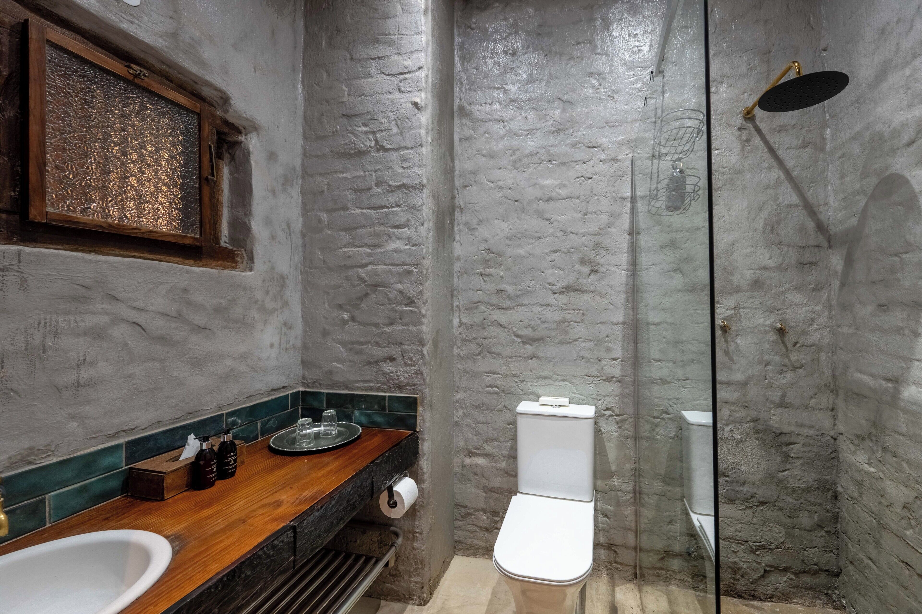 Een badkamer met een houten wastafelmeubel, een witte wastafel, een toilet en een douchecabine met glazen wanden.