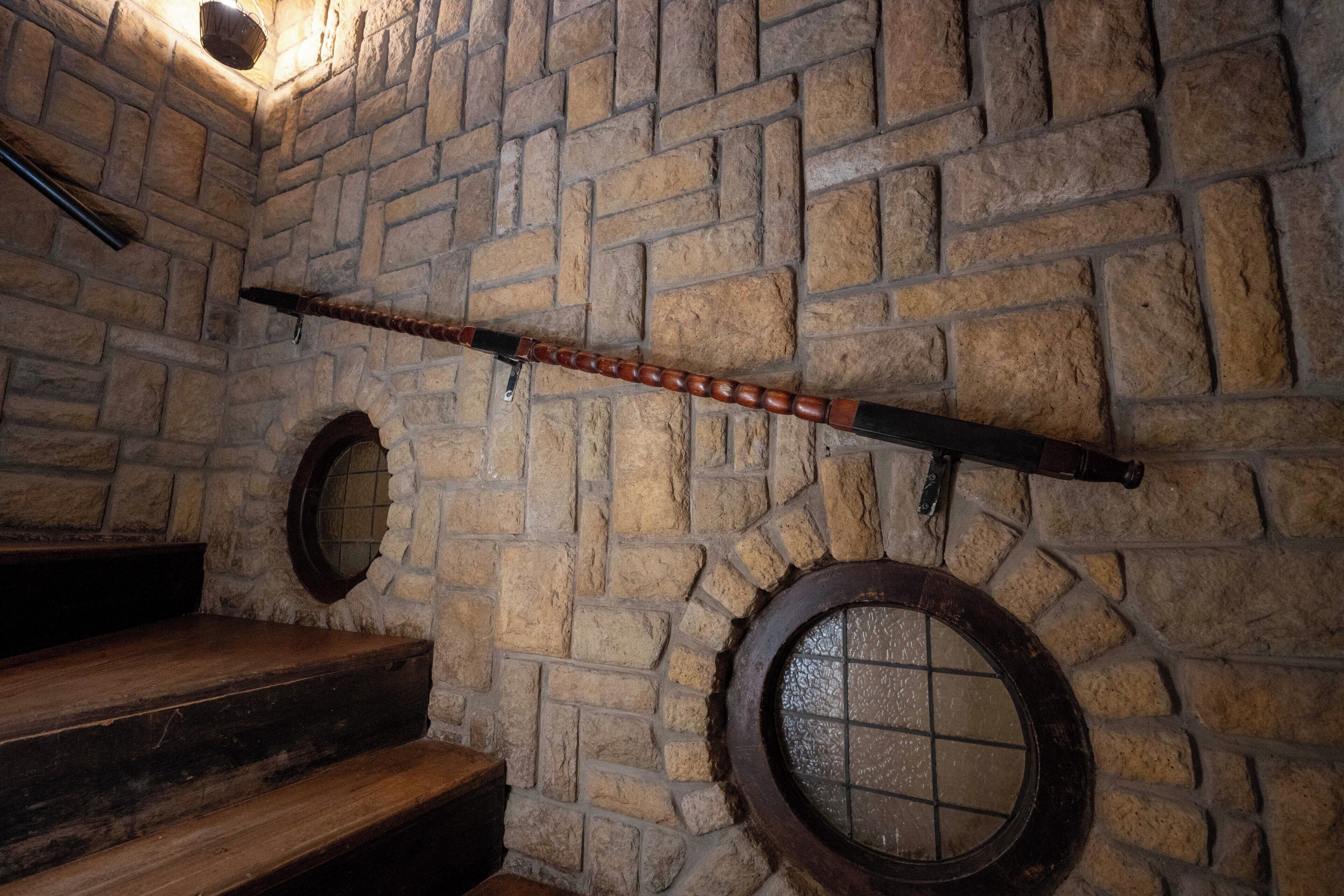 A stone-walled room with wooden steps and a wooden beam across the wall.