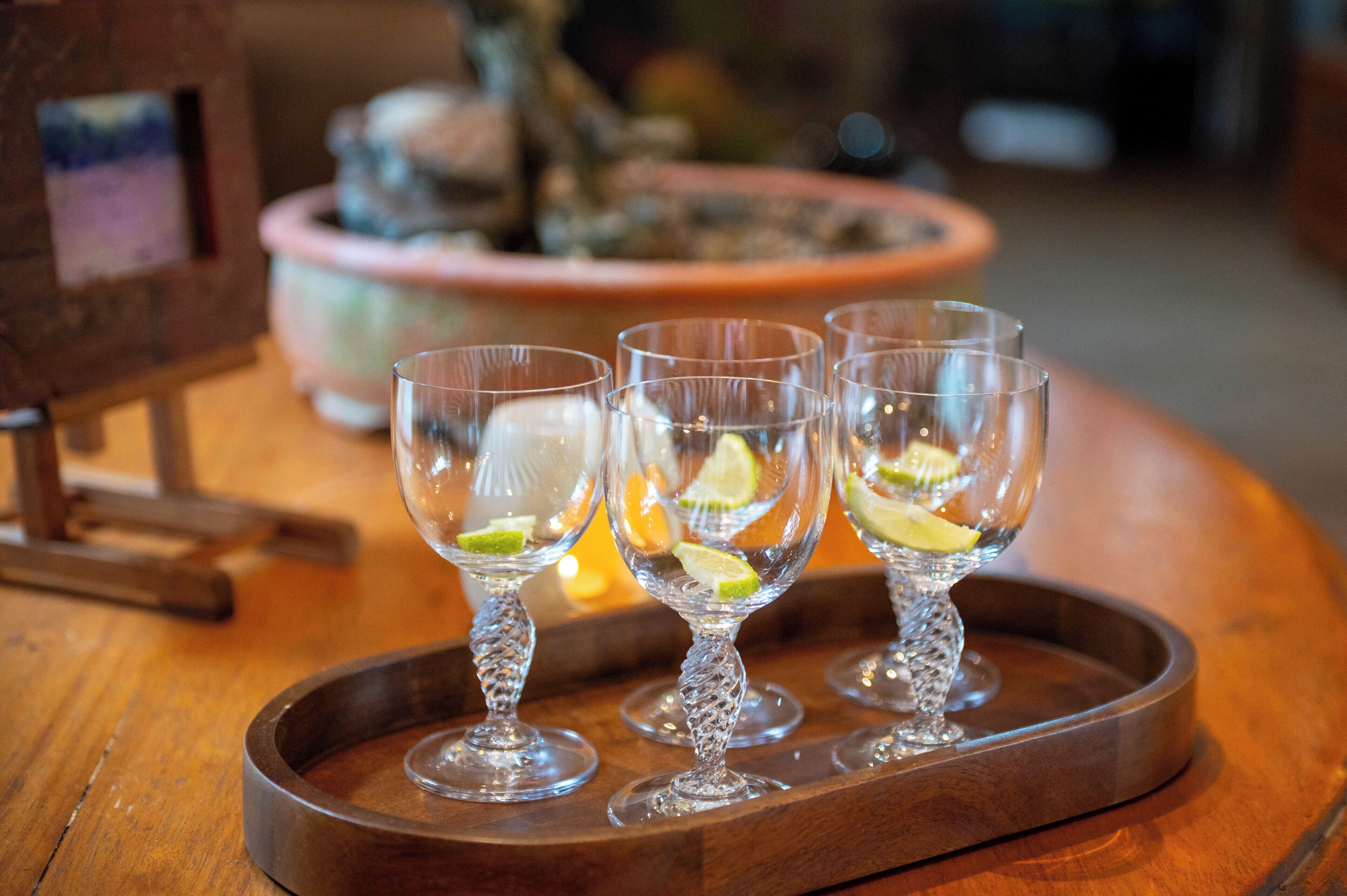 Tre genomskinliga glas med limeskivor på ett träbricka.