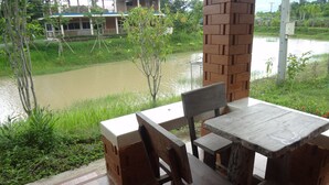 Una mesa y sillas de madera en un balcón con vista al río.