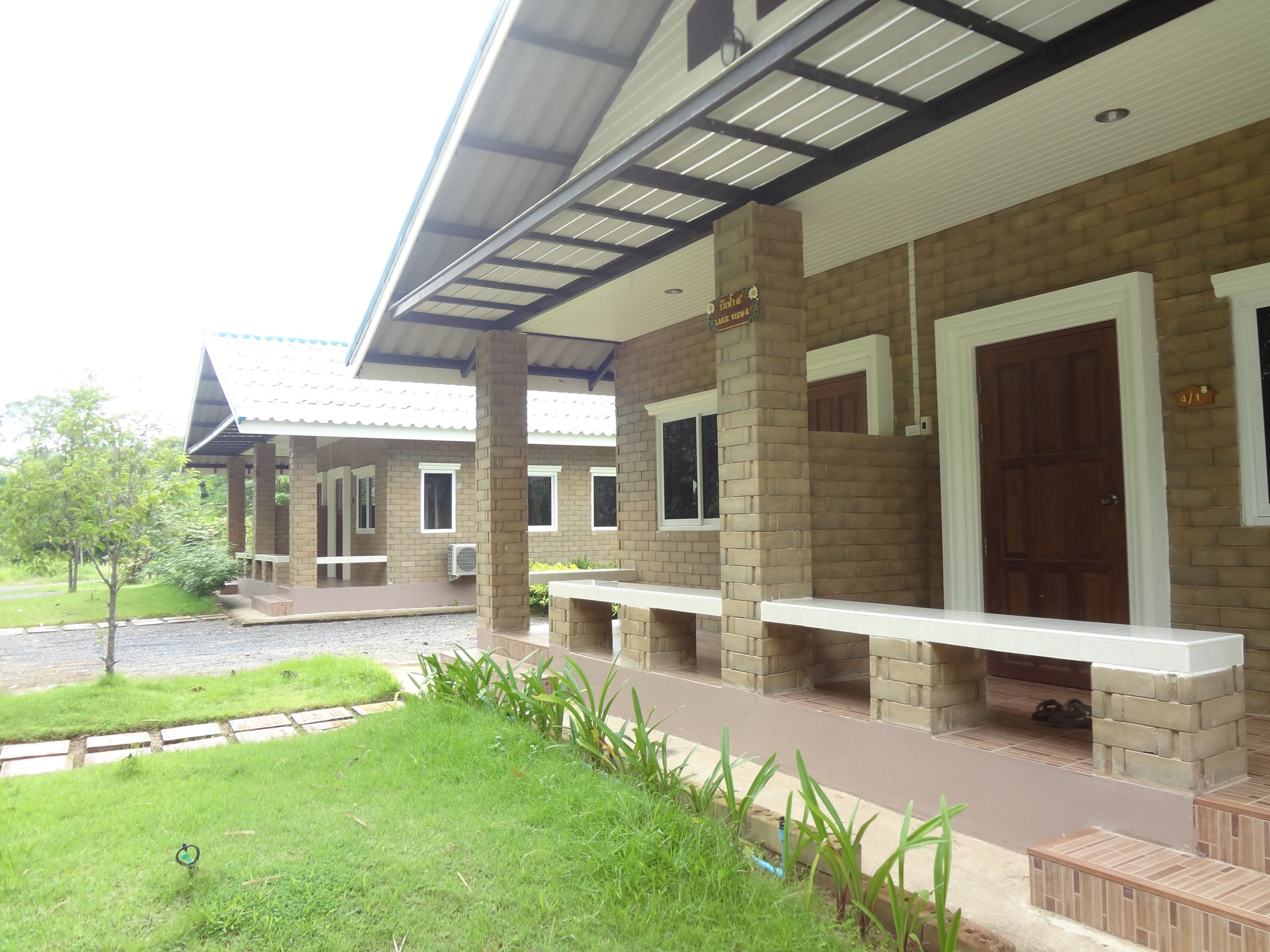 A building with a covered patio area, brick walls, and a wooden door.