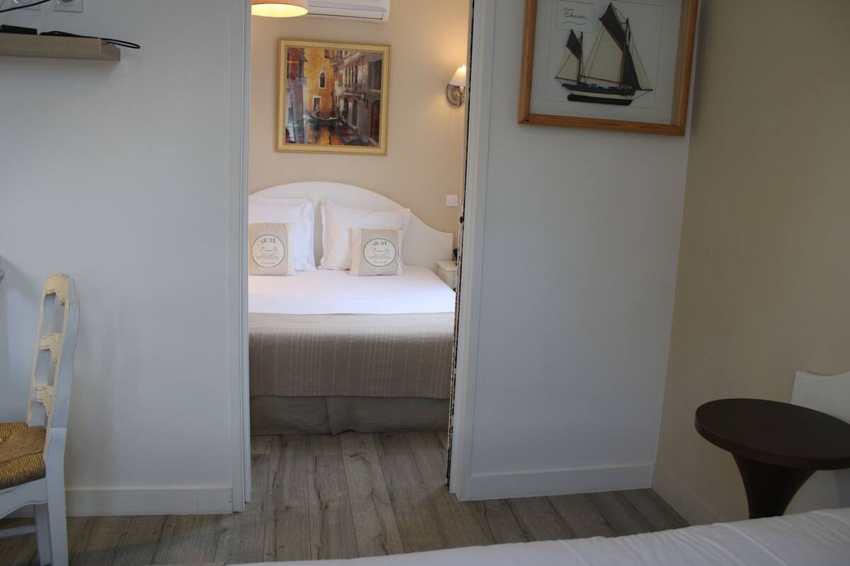 Une chambre d’hôtel avec un lit, une chaise, une petite table et un tableau au mur.
